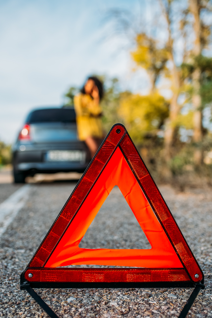 Woman with broken car and triangle
