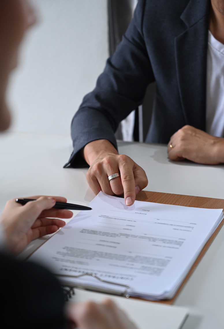 Cropped shot of male lawyer providing law consultation and legal advice to client and showing place for signature on contract document.