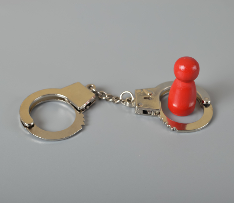 Red wooden people of figure with handcuff locked. Handcuffed convict, law offender and justice concept.