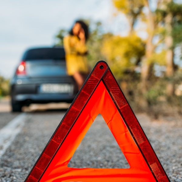 Woman with broken car and triangle