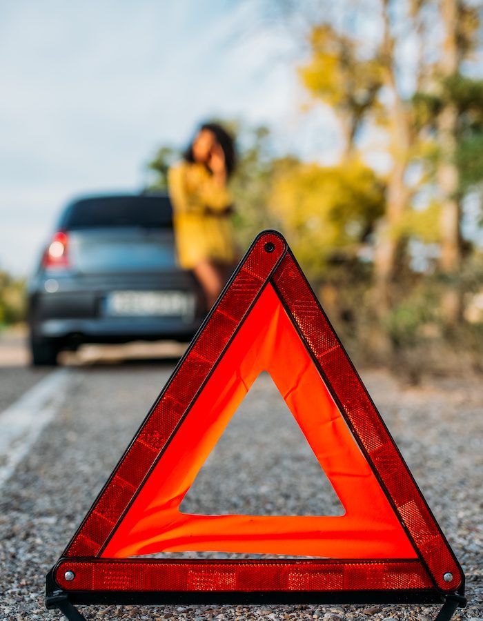Woman with broken car and triangle