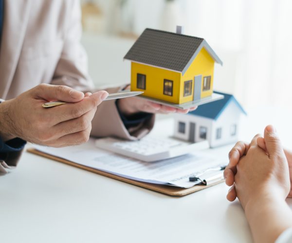 Real estate agent and realtor general liability insurance businessman professional discussing and consultant with house toy model building before sign a contract with law concept.