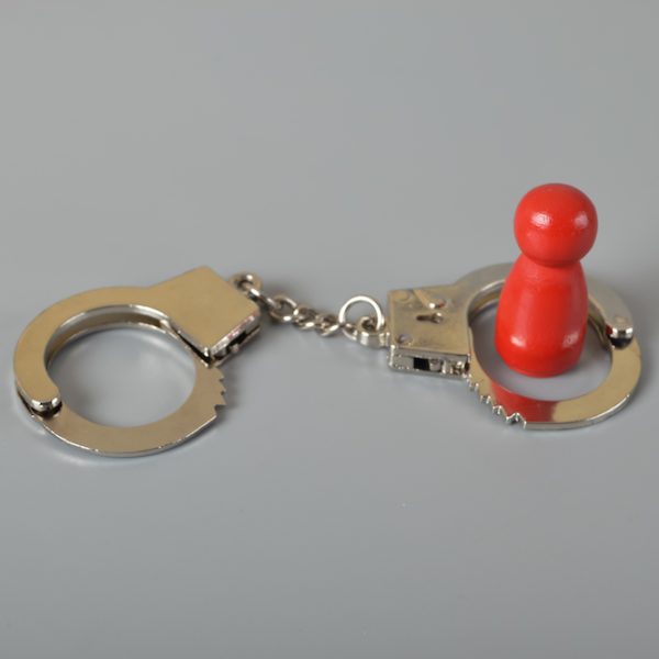Red wooden people of figure with handcuff locked. Handcuffed convict, law offender and justice concept.